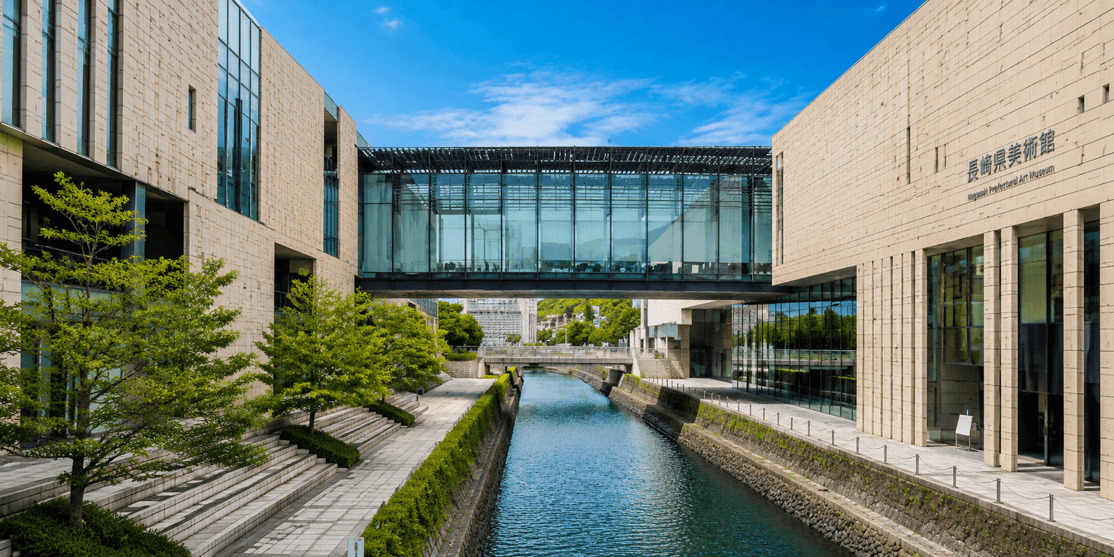 Glass-walled twin buildings of the Nagasaki Prefectural Art Museum bridged above a canal in Dejima-machi, Nagasaki, Japan