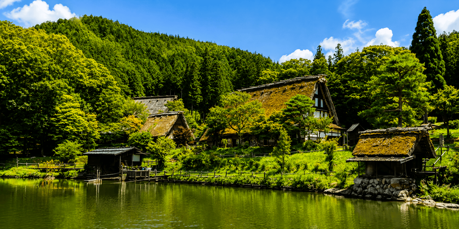 Thatched gassho-zukuri farmhouses of Hida Folk Village reflected in the central pond, Takayama, Japan