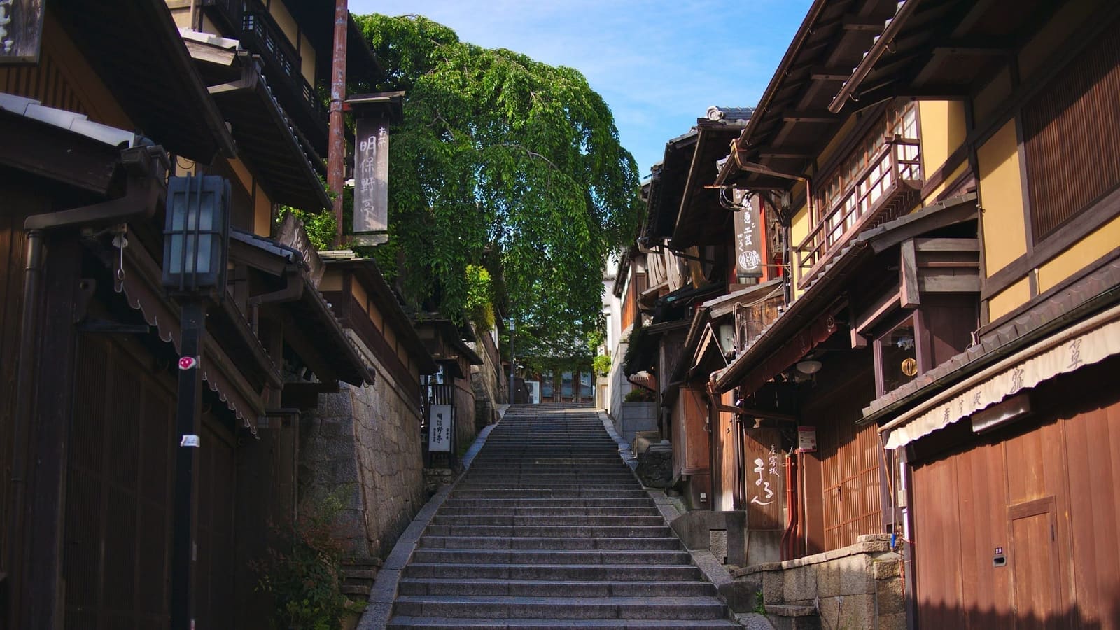 The empty stone steps of Sannenzaka climbing between wooden townhouses under a clear morning sky