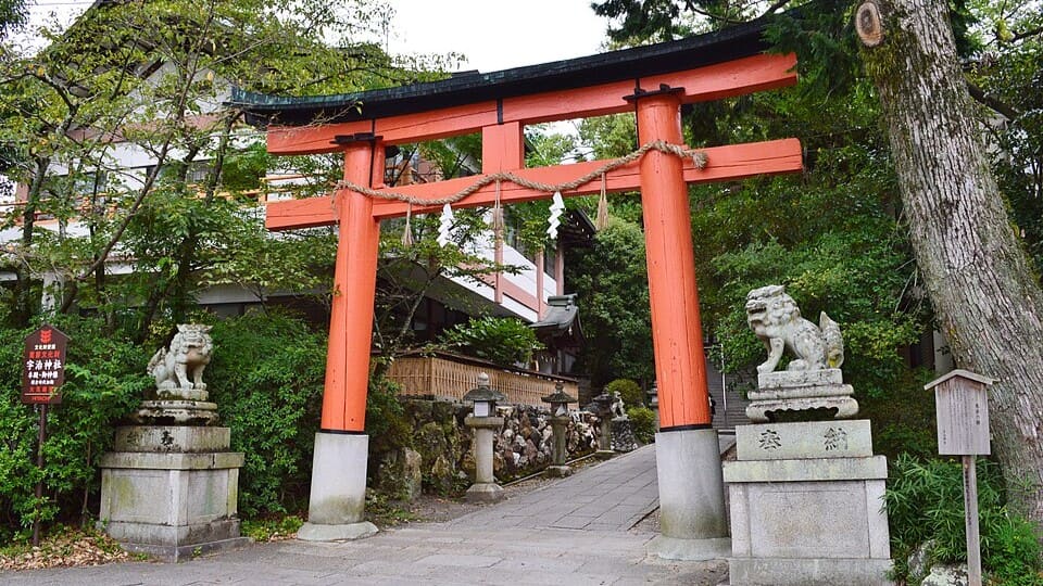 The vermilion torii at the entrance to Uji Shrine, flanked by stone guardian lions