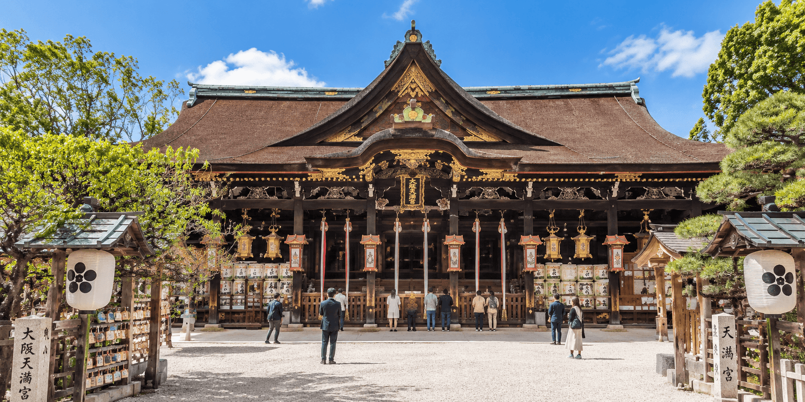 Osaka Tenmangu Shrine's main hall with visitors praying and visible gate signage reading Osaka Tenmangu, Osaka, Japan
