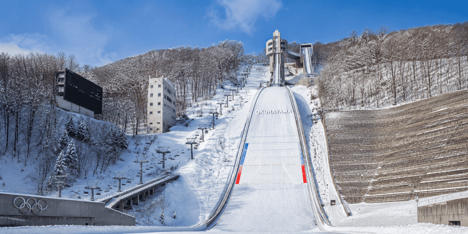 Snow-covered Okurayama ski jump hill with chairlift and Olympic rings monument in Sapporo Japan