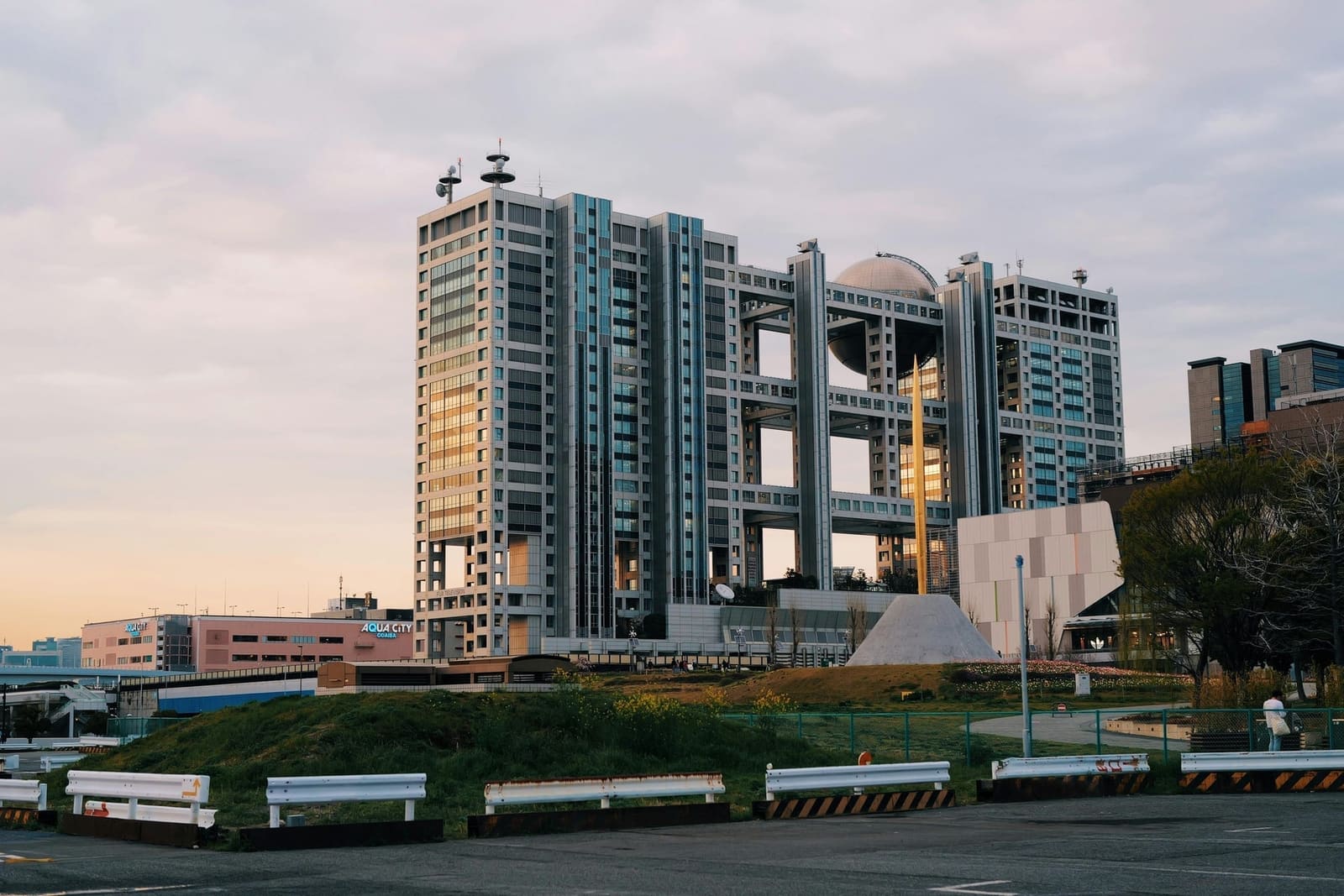 Fuji Television's headquarters building with its distinctive silver sphere observation deck, next to Aqua City Odaiba, at dusk