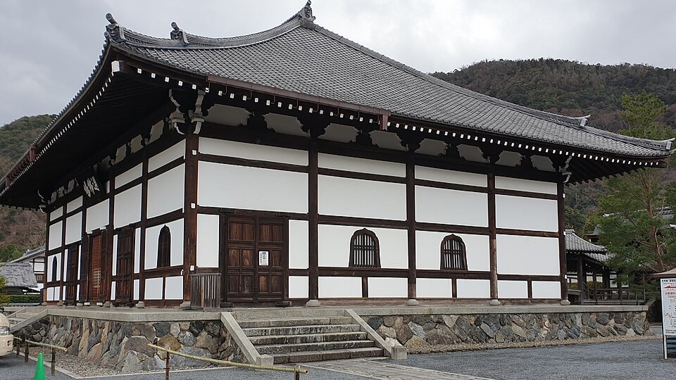 A white-walled Zen hall at Tenryu-ji on a stone base, with wooded hills behind